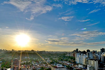Sunrise over dense city skyline with blue sky