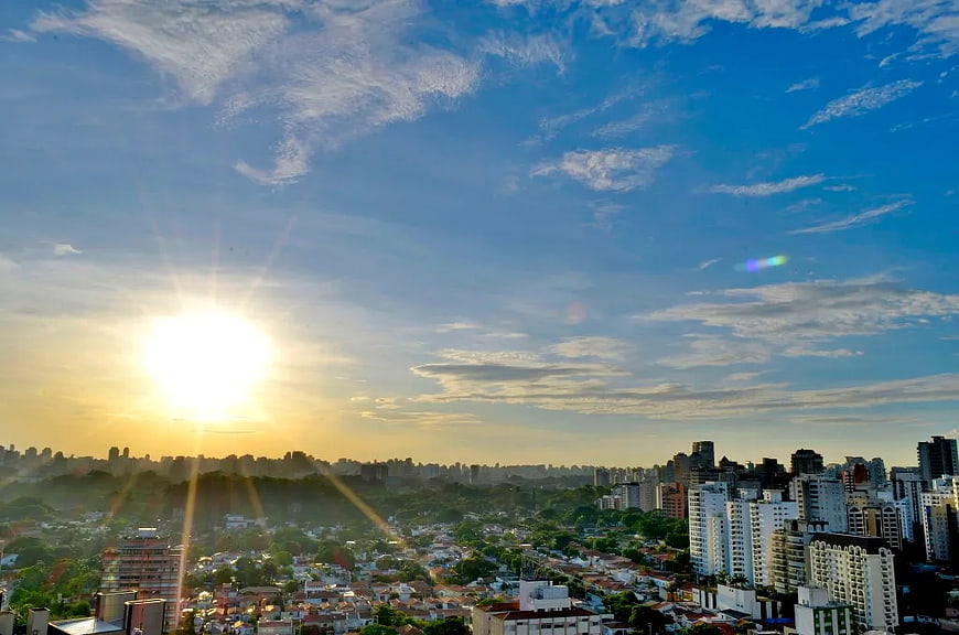 Sunrise over dense city skyline with blue sky