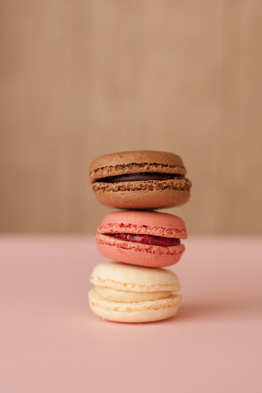 Stack of three colorful macarons on pink background