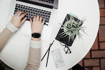 Top-Down View of Woman Typing on Laptop with Workspace Accessories