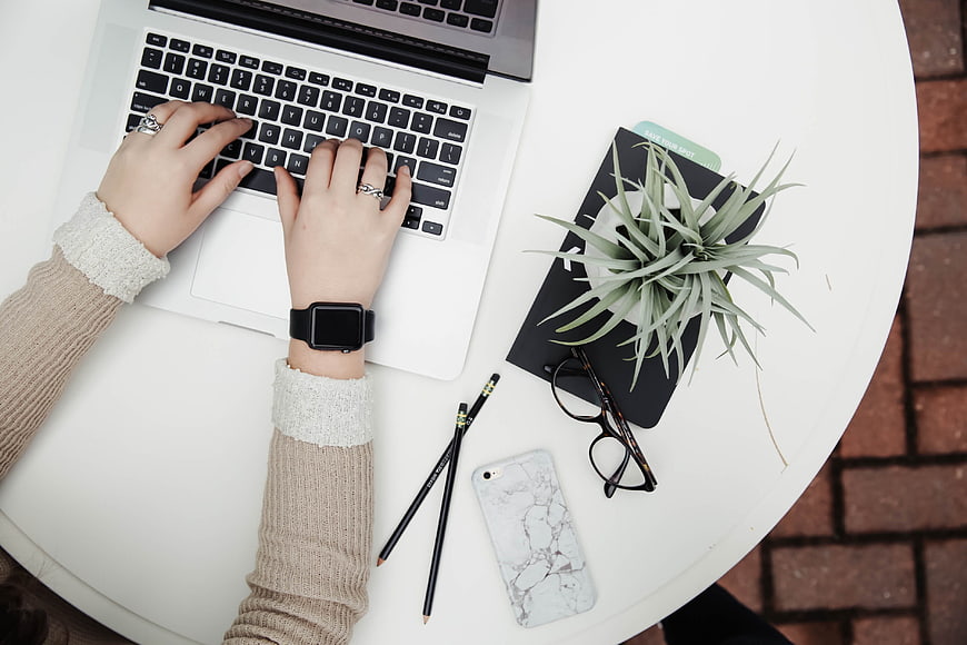 Top-Down View of Woman Typing on Laptop with Workspace Accessories