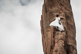 Woman in white dress rock climbing on red sandstone
