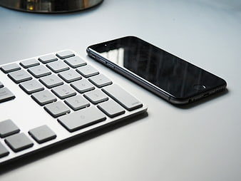 Minimalist workspace with smartphone and keyboard on white desk