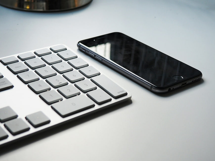 Minimalist workspace with smartphone and keyboard on white desk