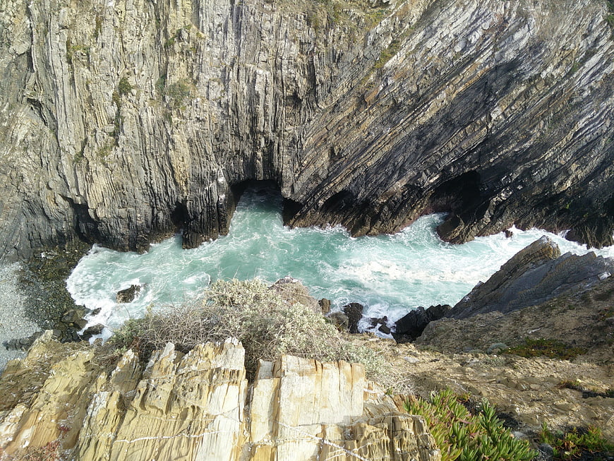 Aerial View of Turquoise Ocean Waves Crashing into Rocky Coastal Caves