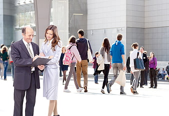 Businessman and woman reviewing clipboard in urban plaza