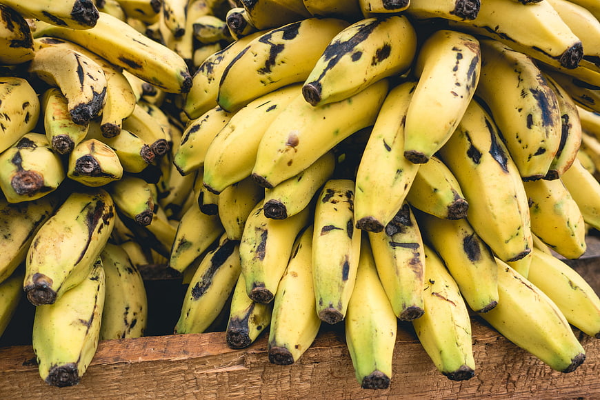 Close-up of ripe yellow bananas with black spots on wood