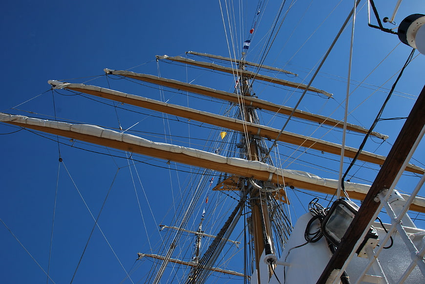 Low angle view of tall ship masts and rigging against blue sky