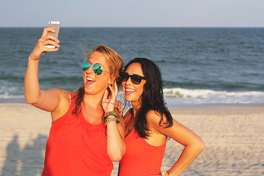 Two happy women taking a selfie on a sunny beach