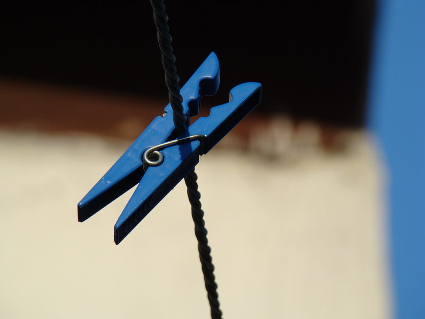 Blue plastic clothespin on black rope with blurred background