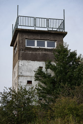 Abandoned concrete watchtower with overgrown vegetation