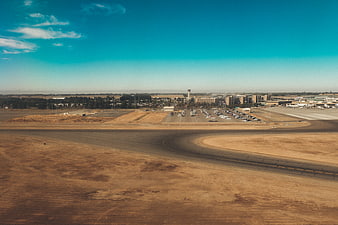 Aerial view of airport runway and parking lot under blue sky