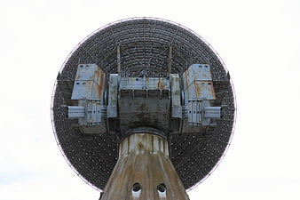 Low angle view of a large, weathered radio telescope dish antenna