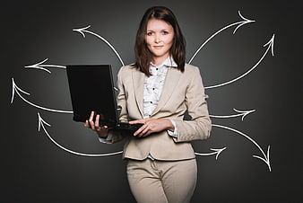 Businesswoman holding laptop with chalk arrows on blackboard background