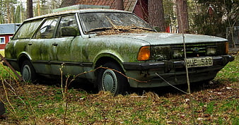 Abandoned moss-covered vintage Ford Taunus station wagon in forest