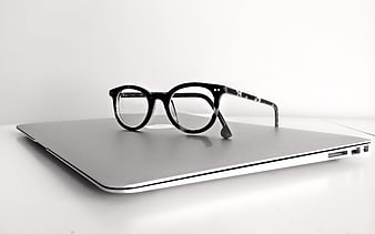 Black Eyeglasses on Closed Silver Laptop