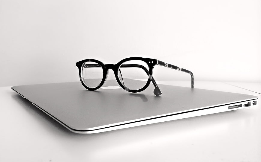 Black Eyeglasses on Closed Silver Laptop