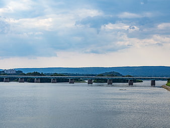 Wide River Bridge with Cloudy Sky and Distant Hills