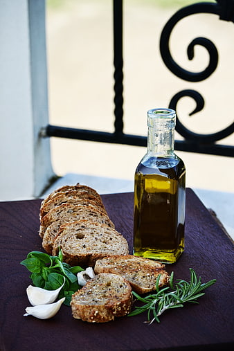 Sliced Seeded Bread, Olive Oil, Garlic, and Herbs on Wooden Board