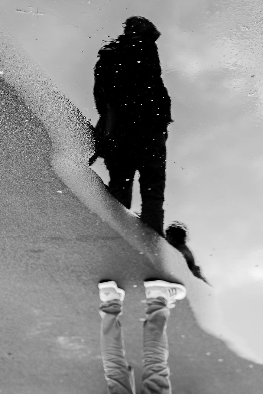 Black and white reflection of man in rain puddle