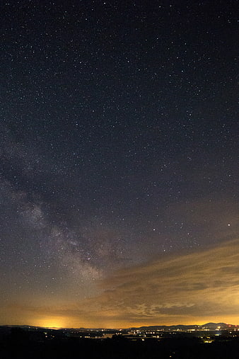 Milky Way galaxy over distant city lights at night