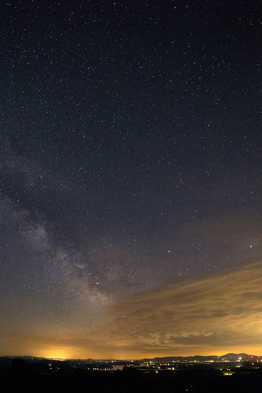 Milky Way galaxy over distant city lights at night