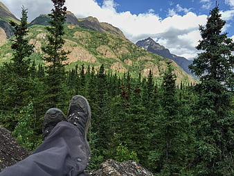 Hiker boots resting on cliff overlooking mountain forest