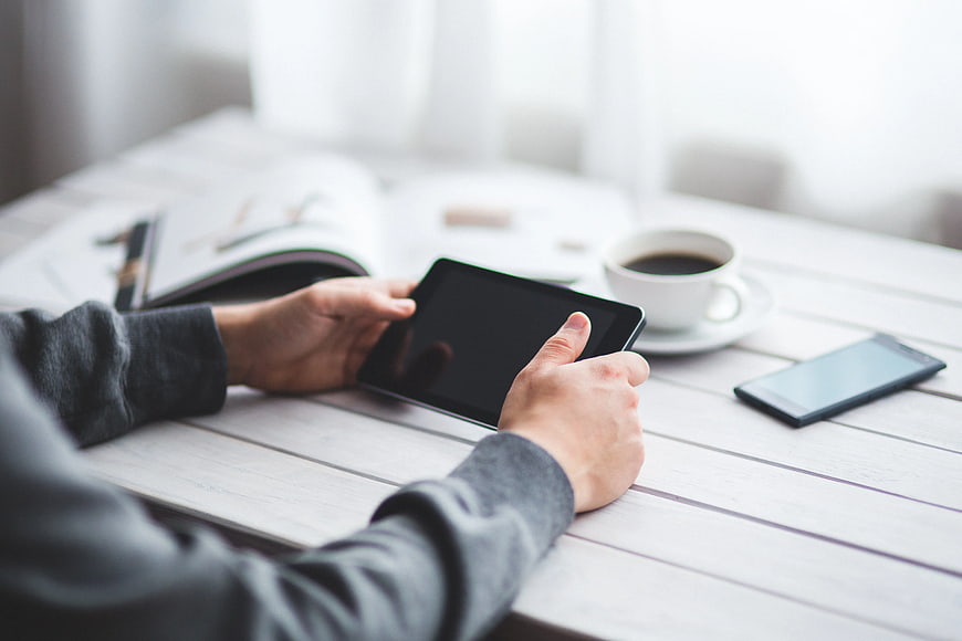 Man using tablet with coffee on wooden table