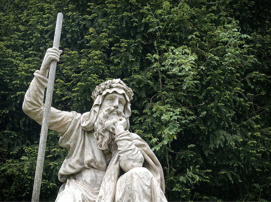 Stone Statue of a Bearded Man with Staff in Garden