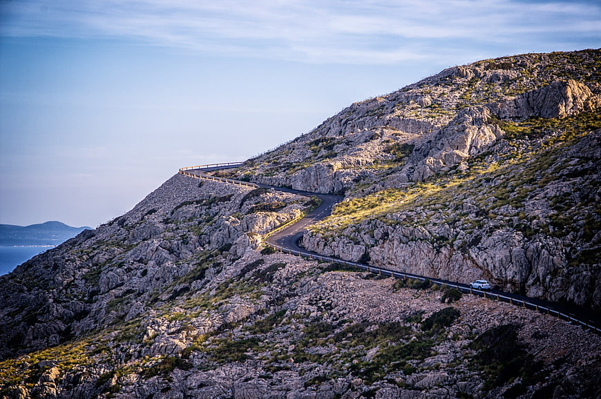 Winding Mountain Road with Car at Sunset