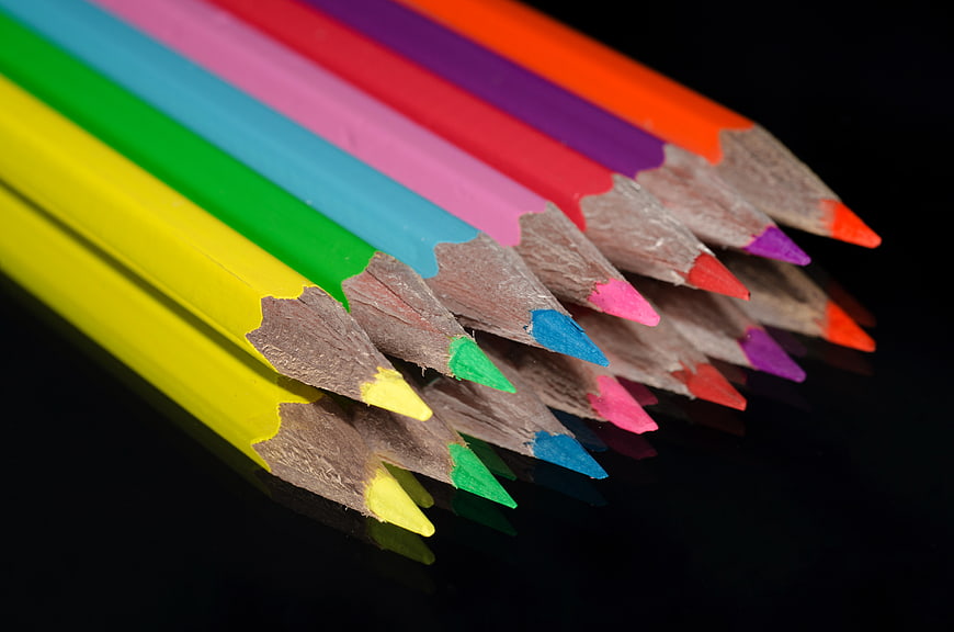Colorful pencils arranged diagonally on a black reflective surface