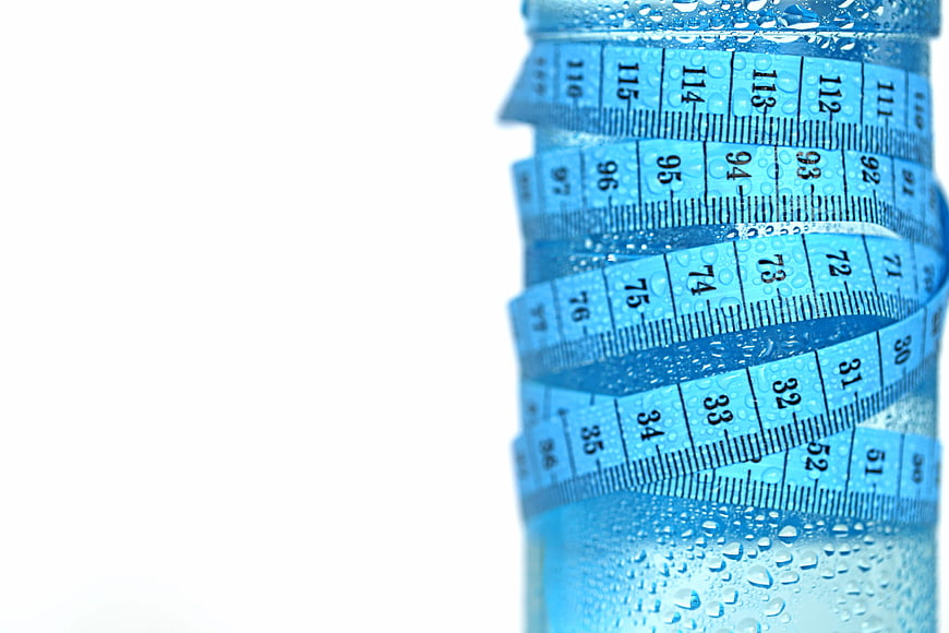Blue measuring tape wrapped around a water bottle with condensation
