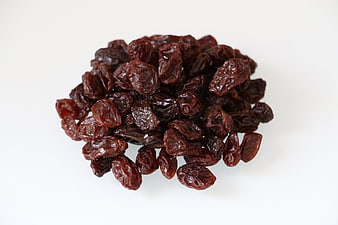 Pile of dark red dried raisins on a clean white background