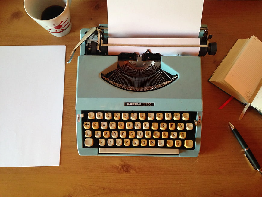 Vintage Teal Typewriter on Wooden Desk with Coffee