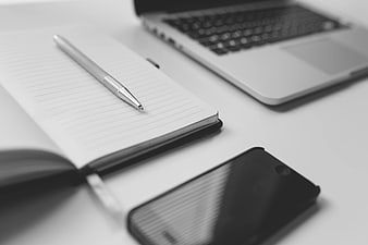 Minimalist workspace with notebook, pen, smartphone, and laptop