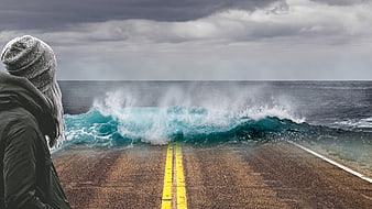 Woman watching ocean wave crash on road