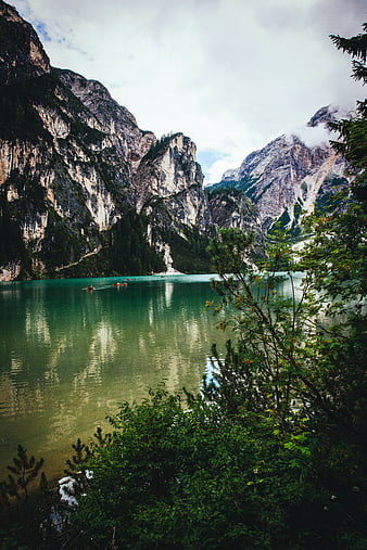 Turquoise alpine lake with boats and towering mountains