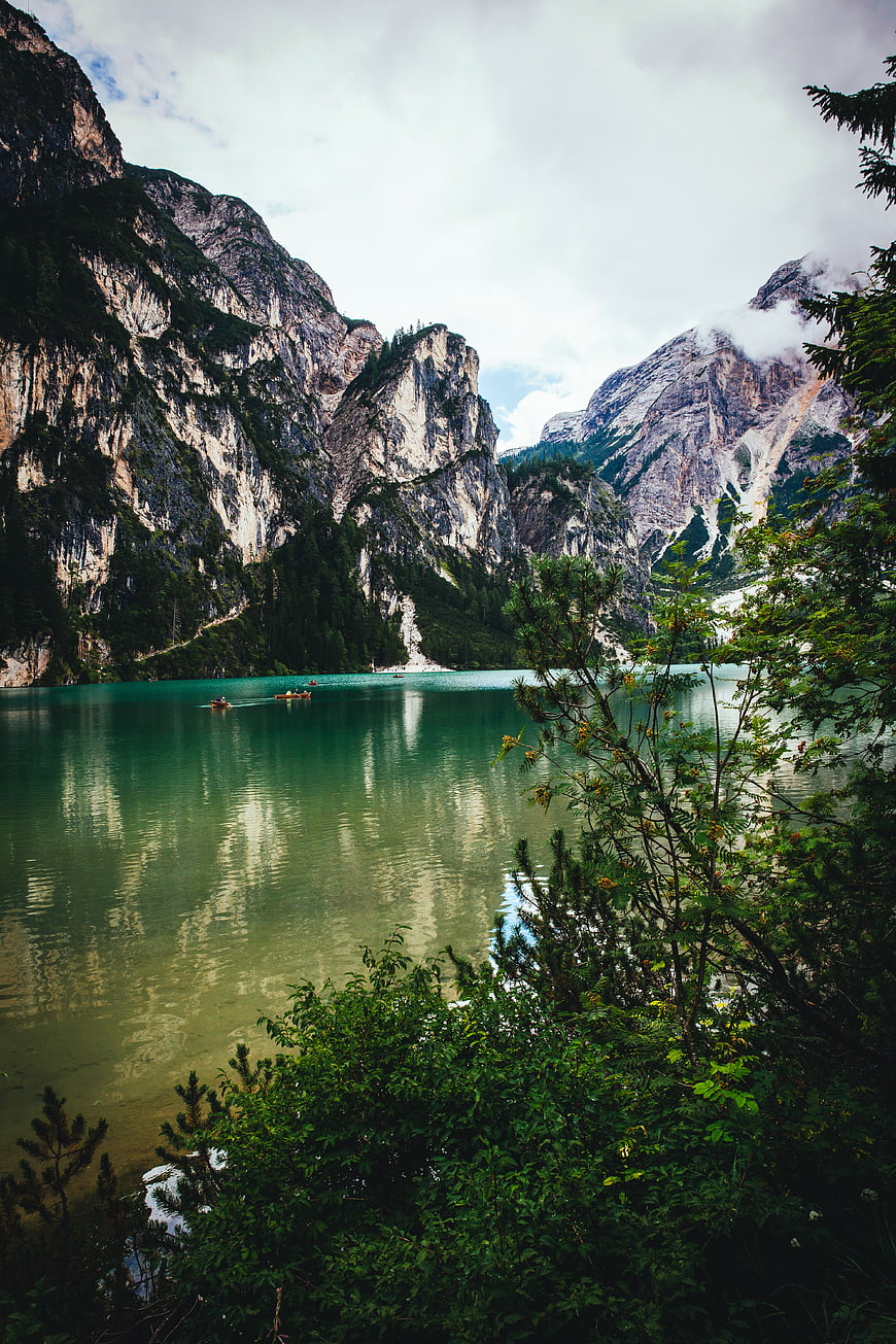 Turquoise alpine lake with boats and towering mountains