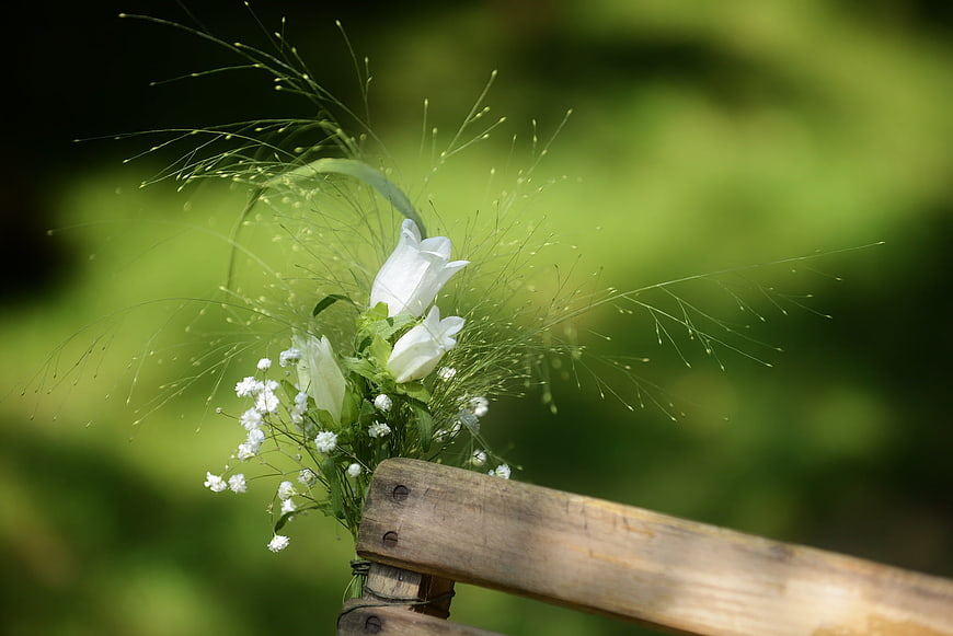 White wedding boutonniere on rustic wooden chair back