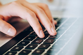 Close-up of female hand typing on laptop keyboard