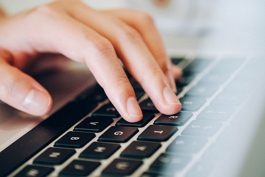 Close-up of female hand typing on laptop keyboard