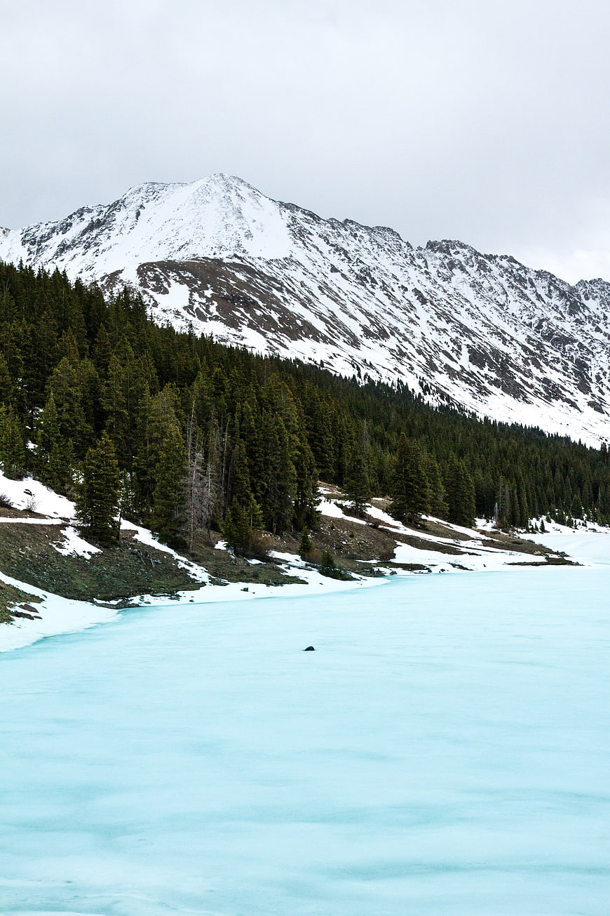 Frozen Alpine Lake with Snowy Mountain and Pine Forest