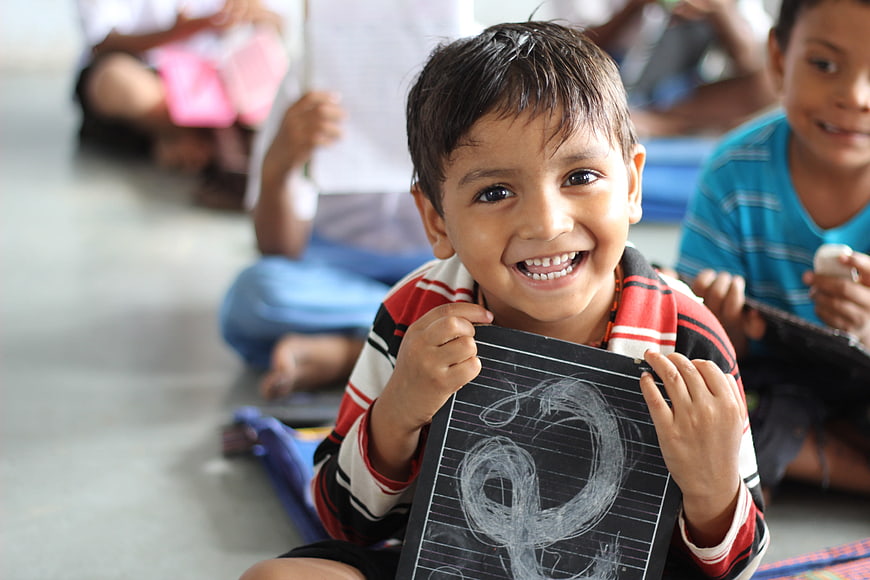 Happy Indian Boy Showing Chalkboard Drawing in Classroom