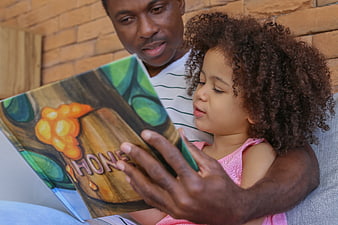 Father Reading Book to Toddler Daughter Indoors