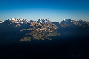 Snow-capped mountain peaks with dramatic shadows and blue sky