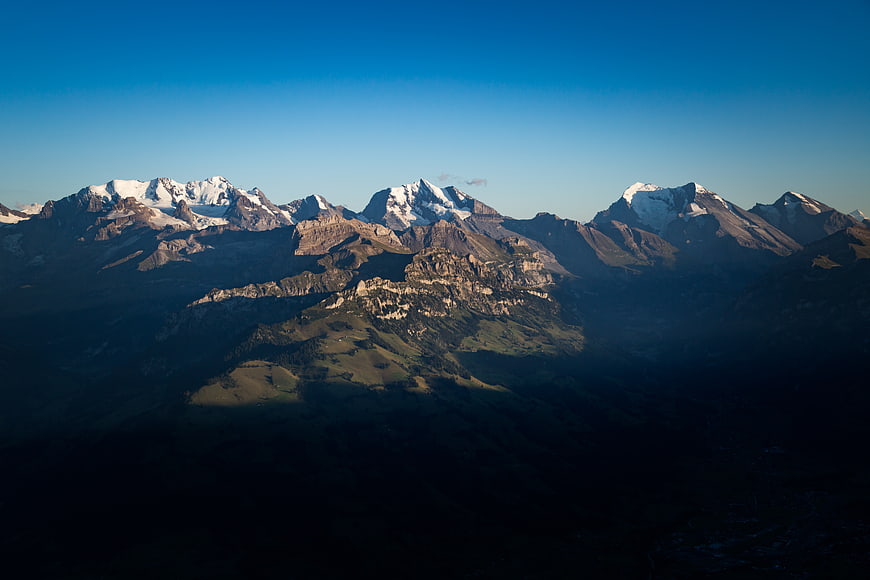 Snow-capped mountain peaks with dramatic shadows and blue sky