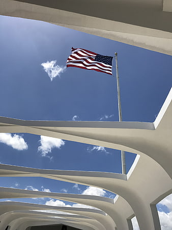 USS Arizona Memorial flag waving against blue sky