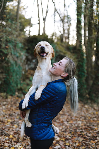 Happy Woman Hugging Golden Retriever in Autumn Forest