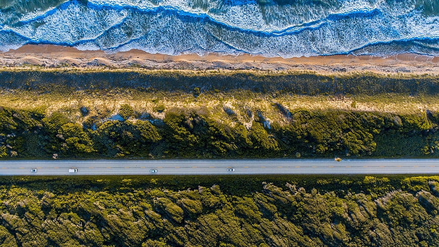 Aerial View of Coastal Highway with Ocean Waves and Forest