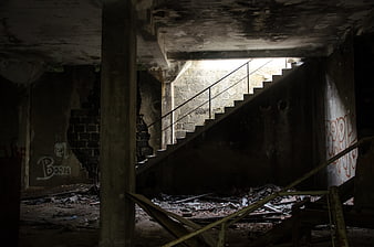 Dark abandoned staircase in dilapidated concrete building with graffiti